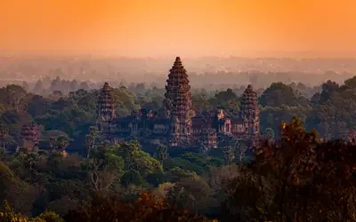 Angkor Wat temple surrounded by forest at sunset