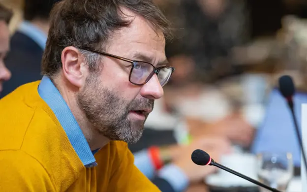 Man with glasses speaking into microphone at a conference
