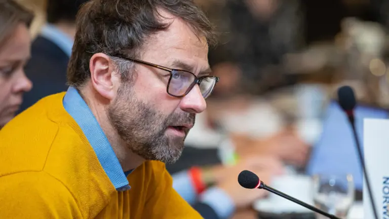 Man with glasses speaking into microphone at a conference