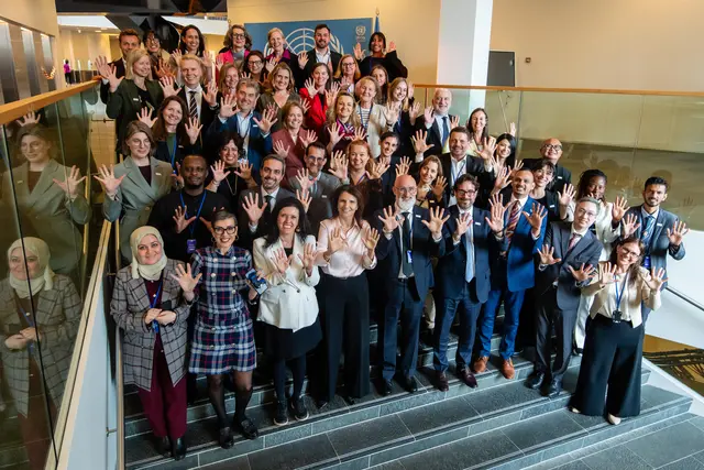 Participants gather for a group photo during the Steering Committee meeting in Denmark in 2026, standing on a staircase inside a conference venue.