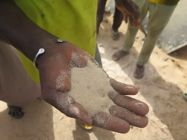 A local man holding soil to demonstrate farming challenges in Dongonkiria