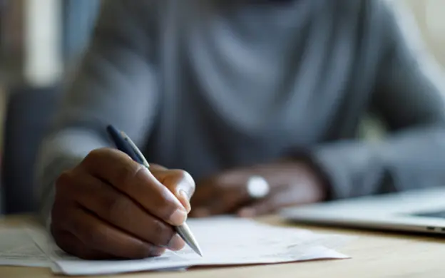 Hand holding pen and writing on paper